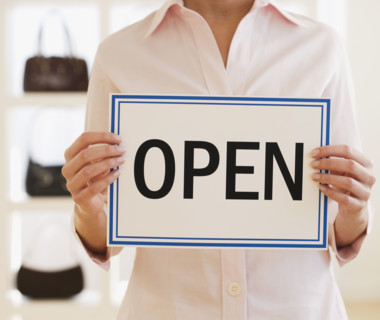 Woman holding Open sign in boutique.