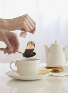 Woman taking tea bag out of cup.