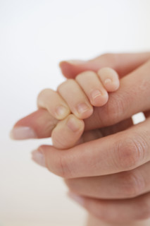 Close up of baby holding mother's hand.