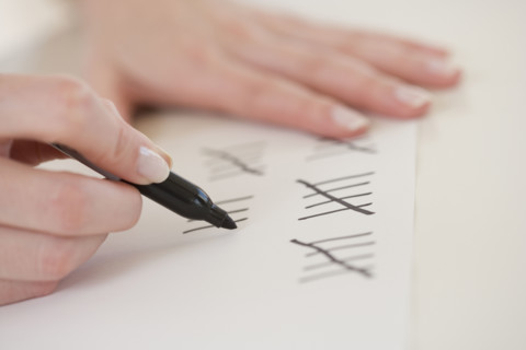 Close up of woman counting on paper.