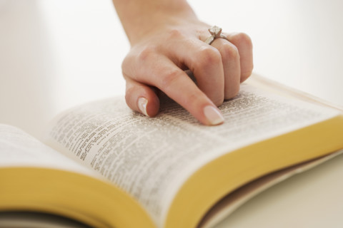 Woman's finger on page in Bible.