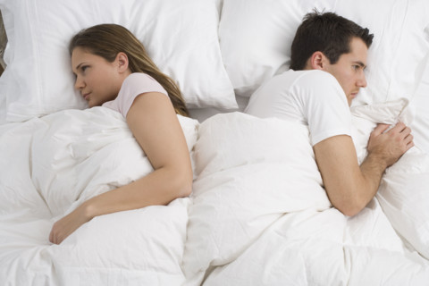 Angry couple laying in bed.