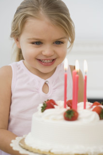 Girl smiling at birthday cake.