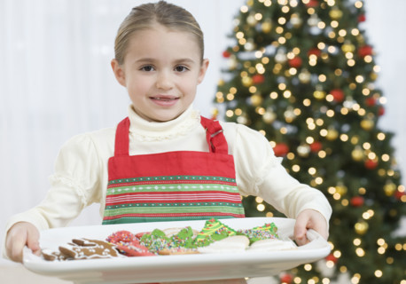 Girl carrying tray of Christmas cookies.