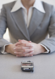 Businesswoman with hands clasped next to cell phone.