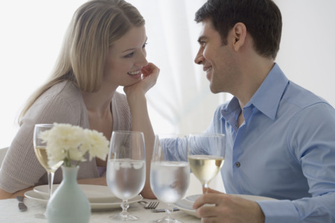 Couple smiling at each other in restaurant.