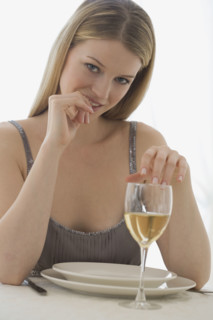 Portrait of woman at table with glass of wine.