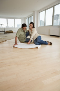 Couple looking at blueprints on floor in new house.