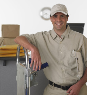 Deliveryman smiling and leaning on hand truck.