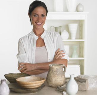 Female potter smiling next to pottery.