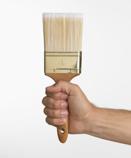 Close up studio shot of man holding paintbrush.