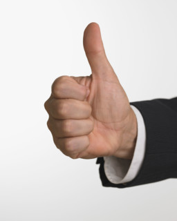 Studio shot of businessman's hand giving thumbs up.
