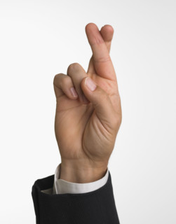 Studio shot of businessman's hand with fingers crossed.