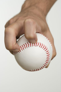 Close up of pitcher holding baseball.