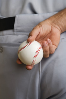Close up baseball pitcher holding baseball behind back.