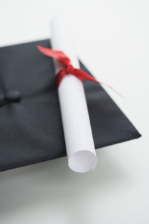 Close up of diploma and graduation cap.