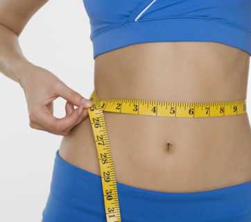 Woman in athletic gear measuring waist.