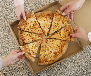 People talking slices of pizza from box.