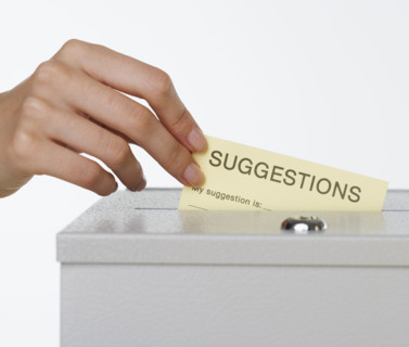 Close up of woman's hand putting card in suggestion box.
