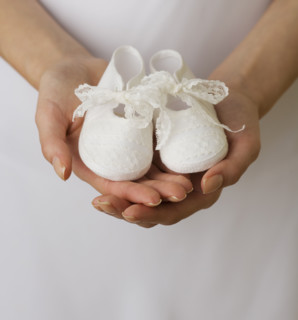 Close up of woman holding baby shoes.
