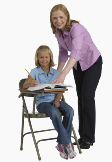 Female teacher helping student at desk.