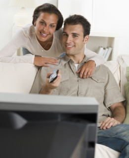 Couple on sofa watching television.