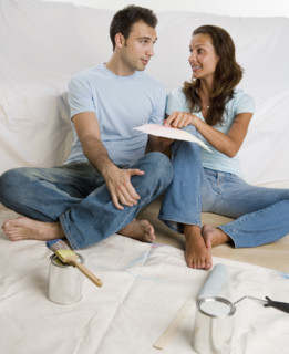 Couple sitting on tarp looking at paint swatches.
