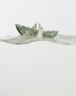 Boat made of US dollar floating on water.