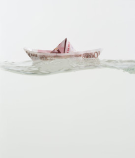 Boat made of paper money floating on water.