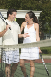 Couple talking on tennis court.