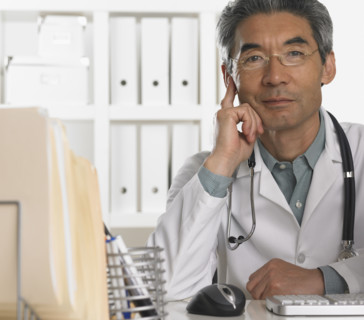 Senior male doctor sitting at desk.