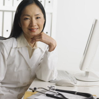 Female doctor sitting at computer smiling.
