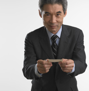 Senior Asian businessman offering business card.