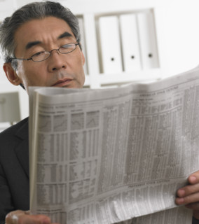 Senior Asian businessman reading newspaper.