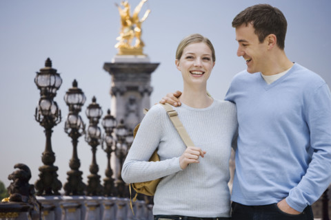 Couple smiling with golden statue in background.