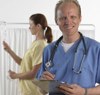 Male doctor smiling and holding chart.