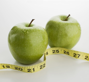 Studio shot of apples and tape measure.