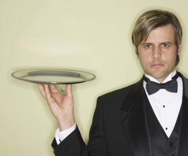 Waiter in tuxedo holding silver platter.