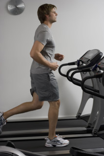 Man running on treadmill at health club.