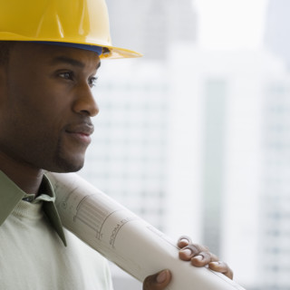 Man in hard hat holding blueprints.