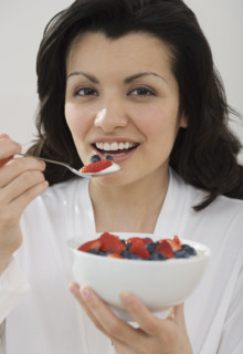 Woman eating bowl of fruit.