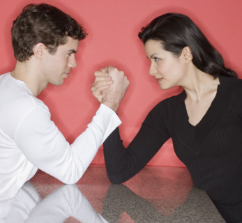 Couple arm wrestling on table.