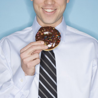 Businessman eating frosted donut.