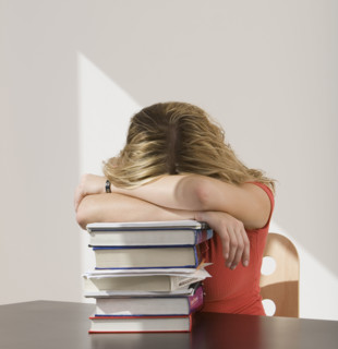 Woman resting head on stack of books.