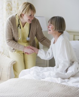 Nurse helping senior woman out of bed.