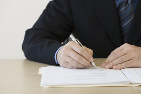 Businessman writing in folder.