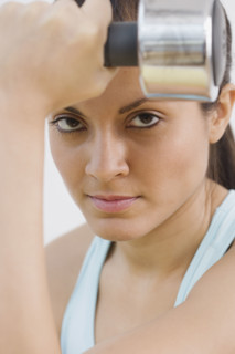 Indian woman holding dumbbell.