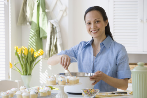 Asian woman stirring batter in kitchen.