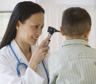 Asian female doctor examining boy’s ear.