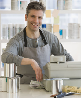 Male clerk at counter of paint store.